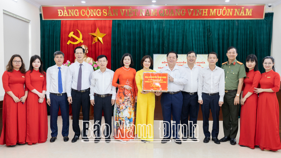 Đồng chí Trưởng Ban Tuyên giáo Trung ương Nguyễn Trọng Nghĩa tặng quà cô và trò trường Tiểu học Nguyễn Tất Thành (thành phố Nam Định).

