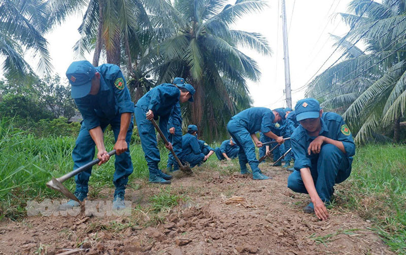 Lực lượng dân quân tự vệ huyện Thạnh Phú tham gia phát hoang đường giao thông nông thôn. Ảnh: Chí Nhân