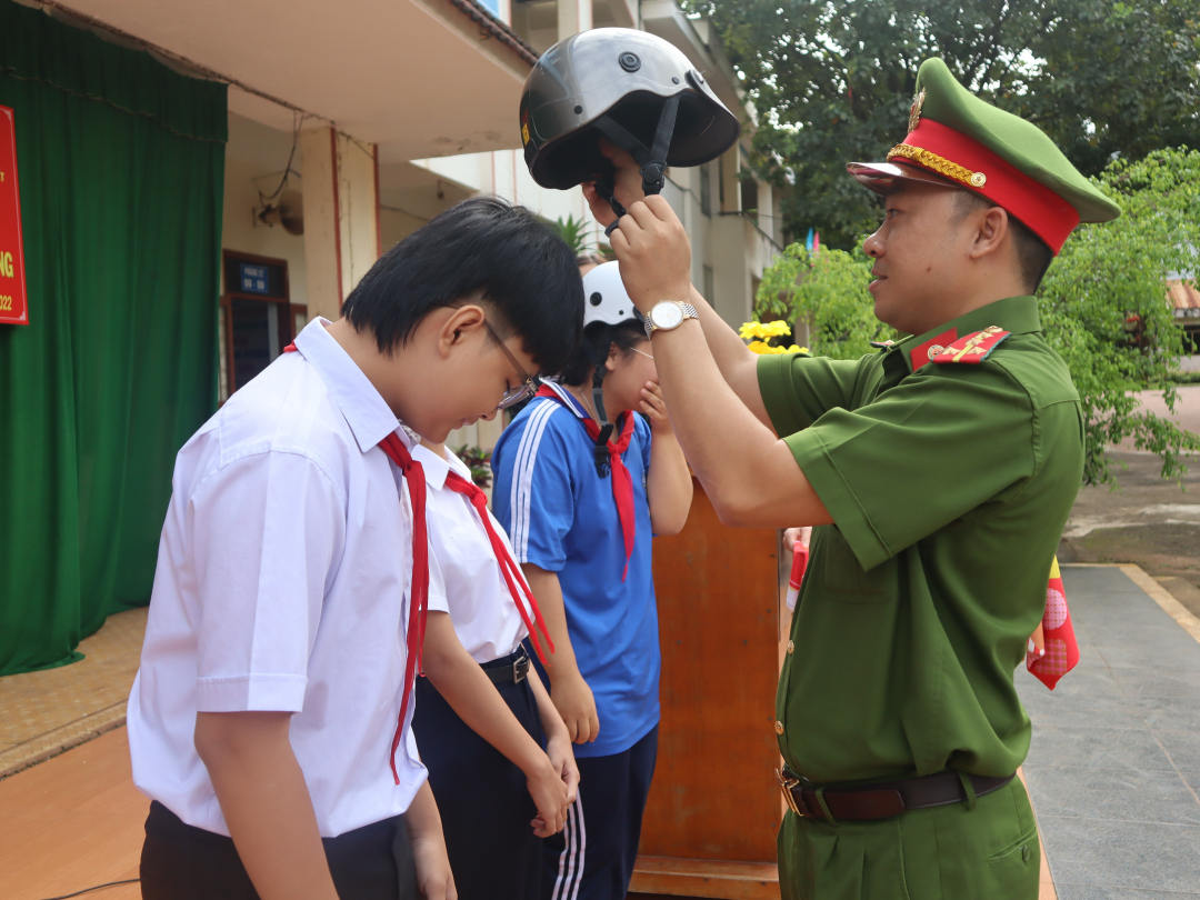 Cán bộ Công an phường Thành Nhất (TP. Buôn Ma Thuột) tặng mũ bảo hiểm cho học sinh.