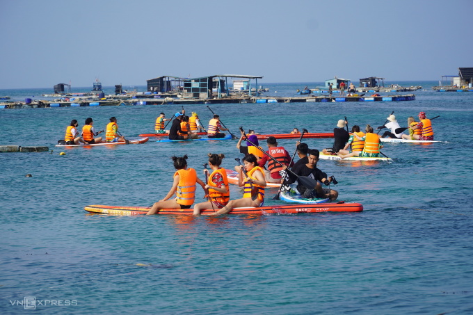 Du khách chèo thuyền surf khám phá rạn san hô, ghé khu nhà lồng bè thưởng thức hải sản tươi sống tại đảo Phú Quý, tỉnh Bình Thuận. Ảnh: Việt Quốc