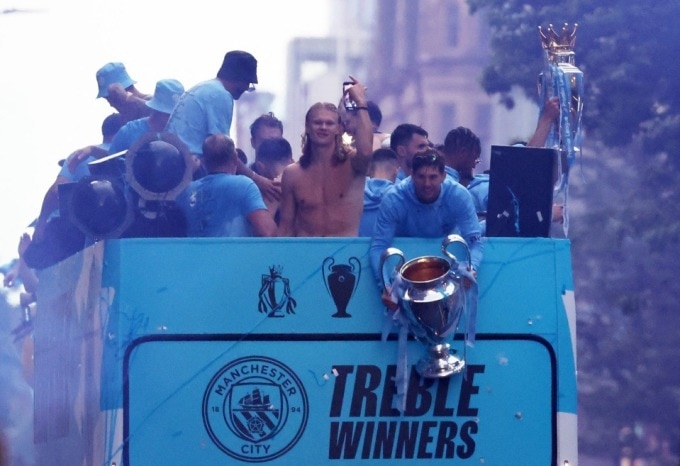 Stones cầm cup Chamions League ở phía đầu xe bus mui trần chở các cầu thủ Man City diễu hành trên đường phố Manchester, Anh mừng ăn ba danh hiệu lớn ngày 12/6. Ảnh: Reuters