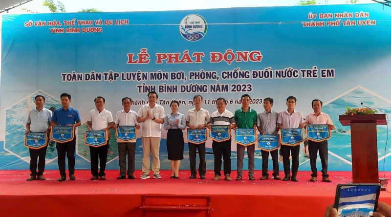 Ông Cao Văn Chóng - PGĐ Sở Văn hóa, Thể thao và Du lịch và bà Nguyễn Thị Kim Nguyên - Phó Chủ tịch UBND thành phố Tân Uyên tặng cờ lưu niệm cho các đơn vị tham dự Lễ Phát động.