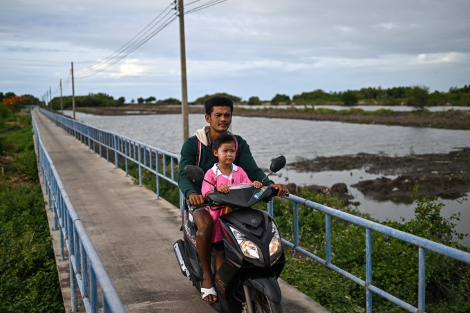 Một ông bố chở con gái đi học tại một ngôi trường bên ngoài làng. Ảnh: AFP