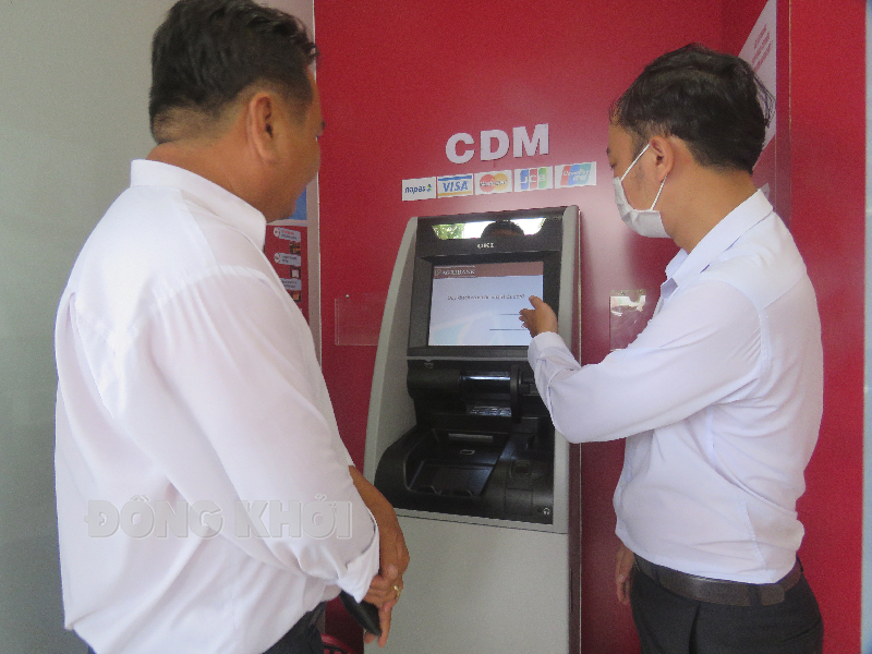 Nhân viên Agribank hướng dẫn khách hàng sử dụng các tiện ích từ máy ATM. Ảnh: Trần Quốc.