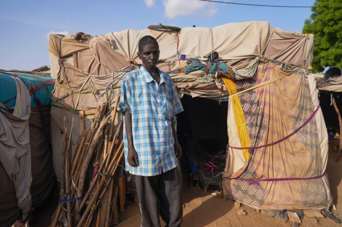 Người đàn ông NIger đứng trước căn lều dựng tạm mà anh sống cùng gia đình ở Niamey ngày 31/7. Ảnh: AP