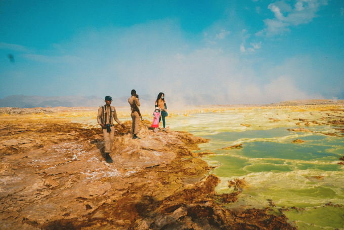 Mai Hương (áo vàng) và con gái chup ảnh tại vùng lòng chảo Danakil, Ethiopia. Đứng cạnh hai mẹ con là các hướng dẫn người địa phương.