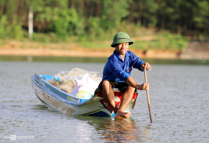 Anh Đặng Văn Tú chèo thuyền đi kiểm tra các lồng bè cá nuôi tại đập Khe Là. Ảnh: Đức Hùng