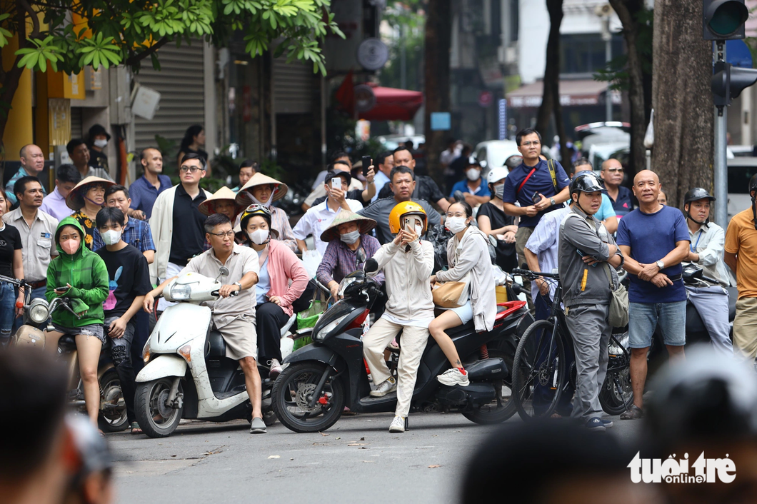 Người dân Hà Nội theo dõi đoàn xe của tổng thống Mỹ di chuyển trên đường - Ảnh: DANH KHANG