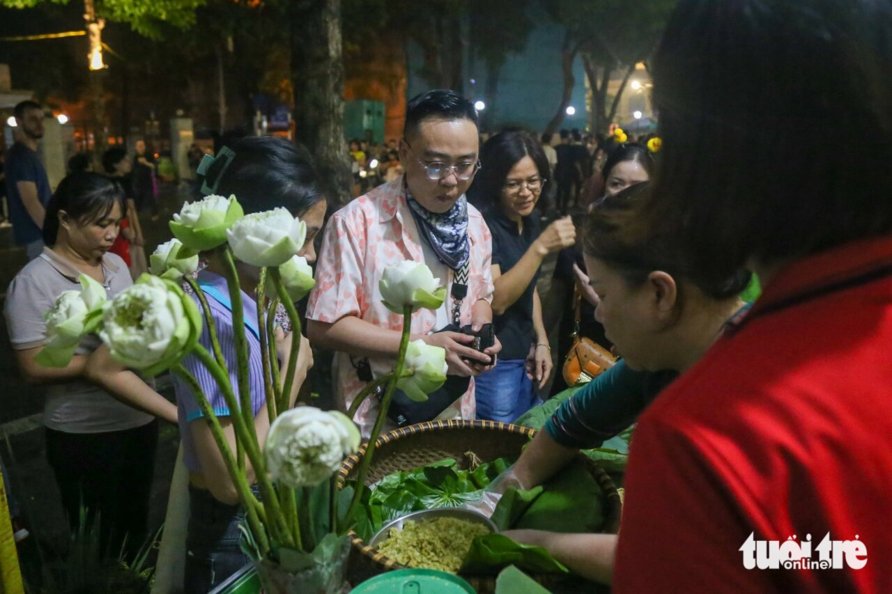 Nhiều du khách thích thú trải nghiệm cốm làng Vòng ngay tại phố đi bộ hồ Hoàn Kiếm trong tiết thu mát mẻ của Hà Nội - Ảnh: HÀ QUÂN