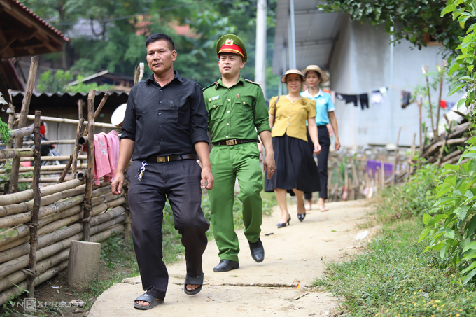 Ông Thuận (áo đen, đi đầu) cùng cán bộ công an, hội phụ nữ xã Hữu Kiệm đến nhà người dân ở bản Đỉnh Sơn 2, tuyên truyền không bán bào thai. Ảnh: Đức Hùng