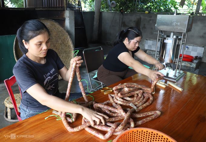 Chị Bảo (góc phải) cùng một lao động đang điều chỉnh máy để tạo lạp xưởng tươi. Ảnh: Đức Hùng