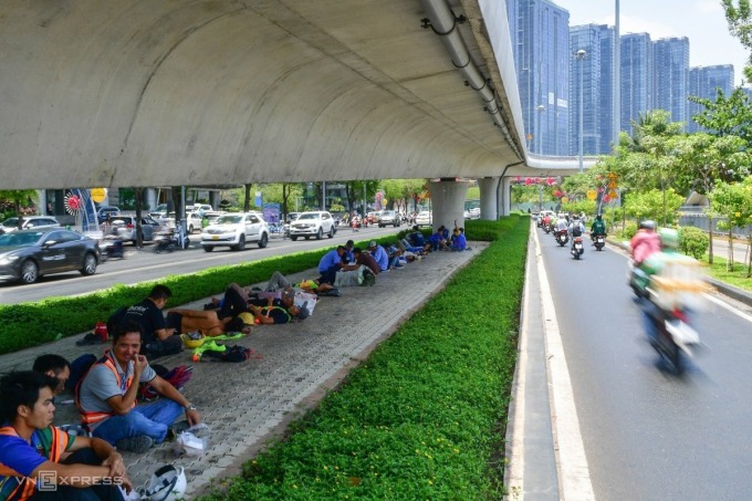 Giờ nghỉ trưa hàng chục công nhân ăn uống, ngủ dưới chân cầu Ba Son, đoạn trên đường Tôn Đức Thắng, quận 1. Ảnh: Quỳnh Trần