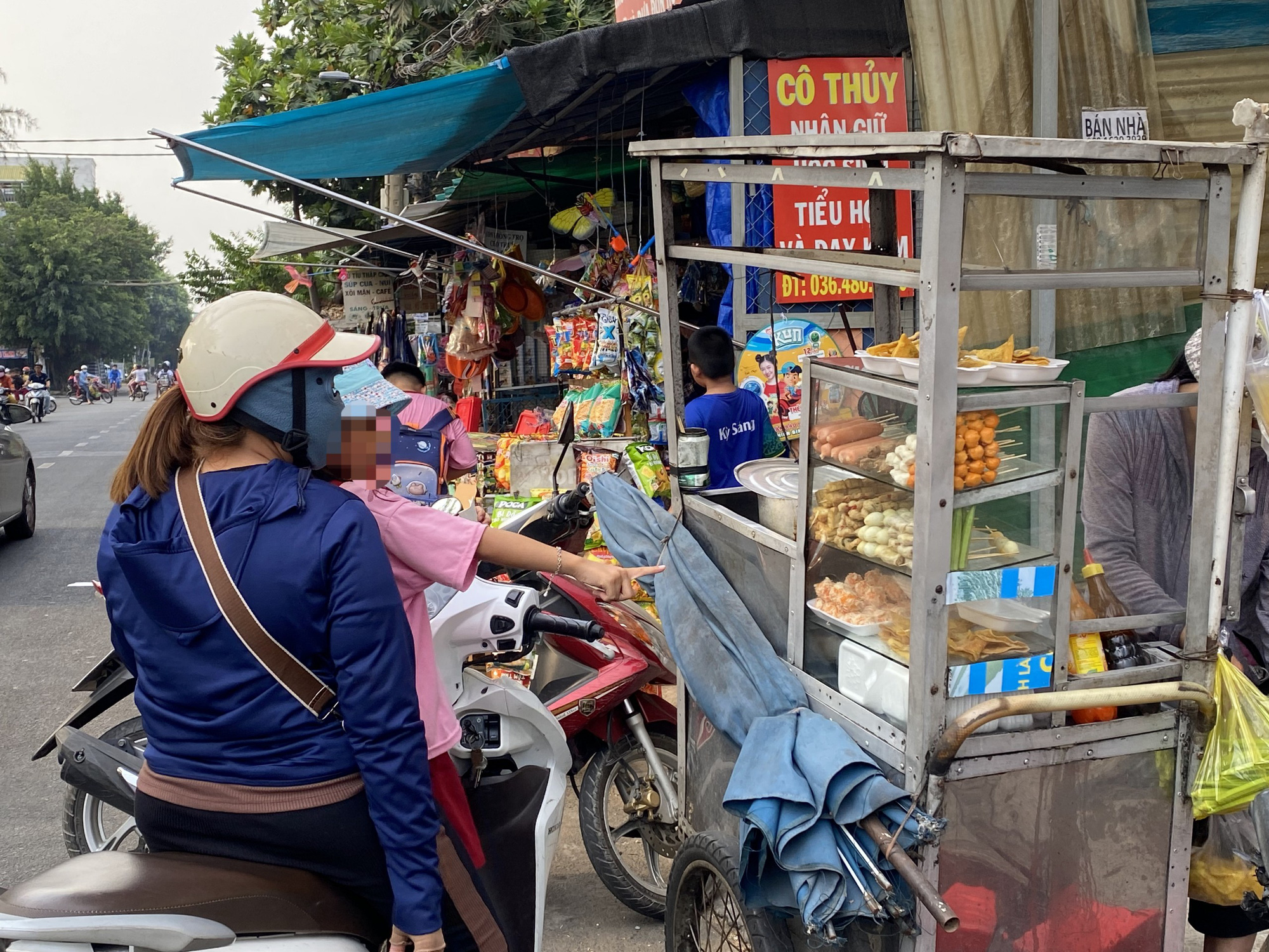 Phụ huynh mua đồ ăn vặt cho con vào giờ ra về trước cổng trường tiểu học - Ảnh: VŨ HIÊN