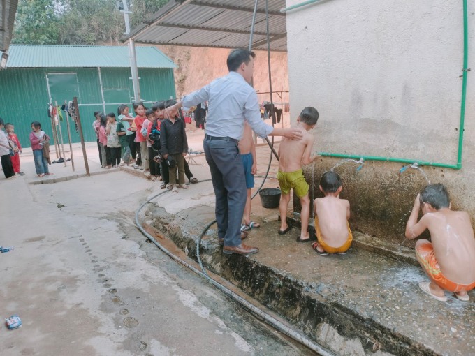 Các học sinh tại trường PTDTBT TH và THCS Tân Lập, xã Háng Lìa, huyện Điện Biên Đông, xếp hàng chờ thầy Giàng A Sử tắm giữa giờ ra chơi, chiều 22/4. Ảnh: Nhà trường cung cấp