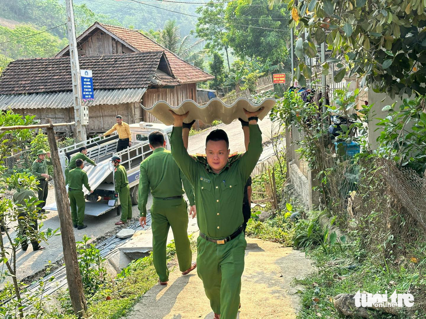 Các chiến sĩ công an bốc vác từng mái ngói lên để lợp lại nhà cho người dân - Ảnh: TÂM PHẠM