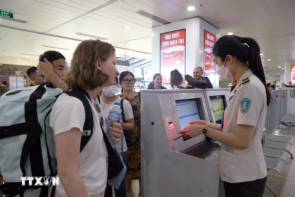 Nhân viên an ninh hàng không kiểm tra giấy tờ hành khách trước khi vào khu vực soi chiếu. (Ảnh: Huy Hùng/TTXVN)