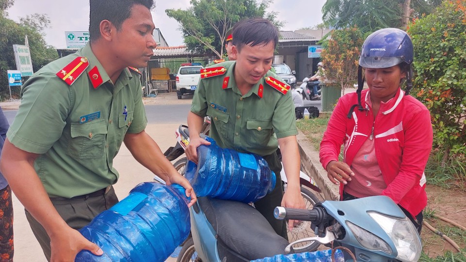 C&aacute;c chiến sĩ C&ocirc;ng an S&oacute;c Trăng trao nước sạch cho người d&acirc;n.