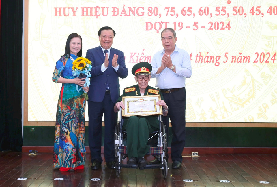 B&iacute; thư Th&agrave;nh ủy Đinh Tiến Dũng trao Huy hiệu 80 năm tuổi Đảng v&agrave; tặng hoa ch&uacute;c mừng đồng ch&iacute; Việt Chiến.