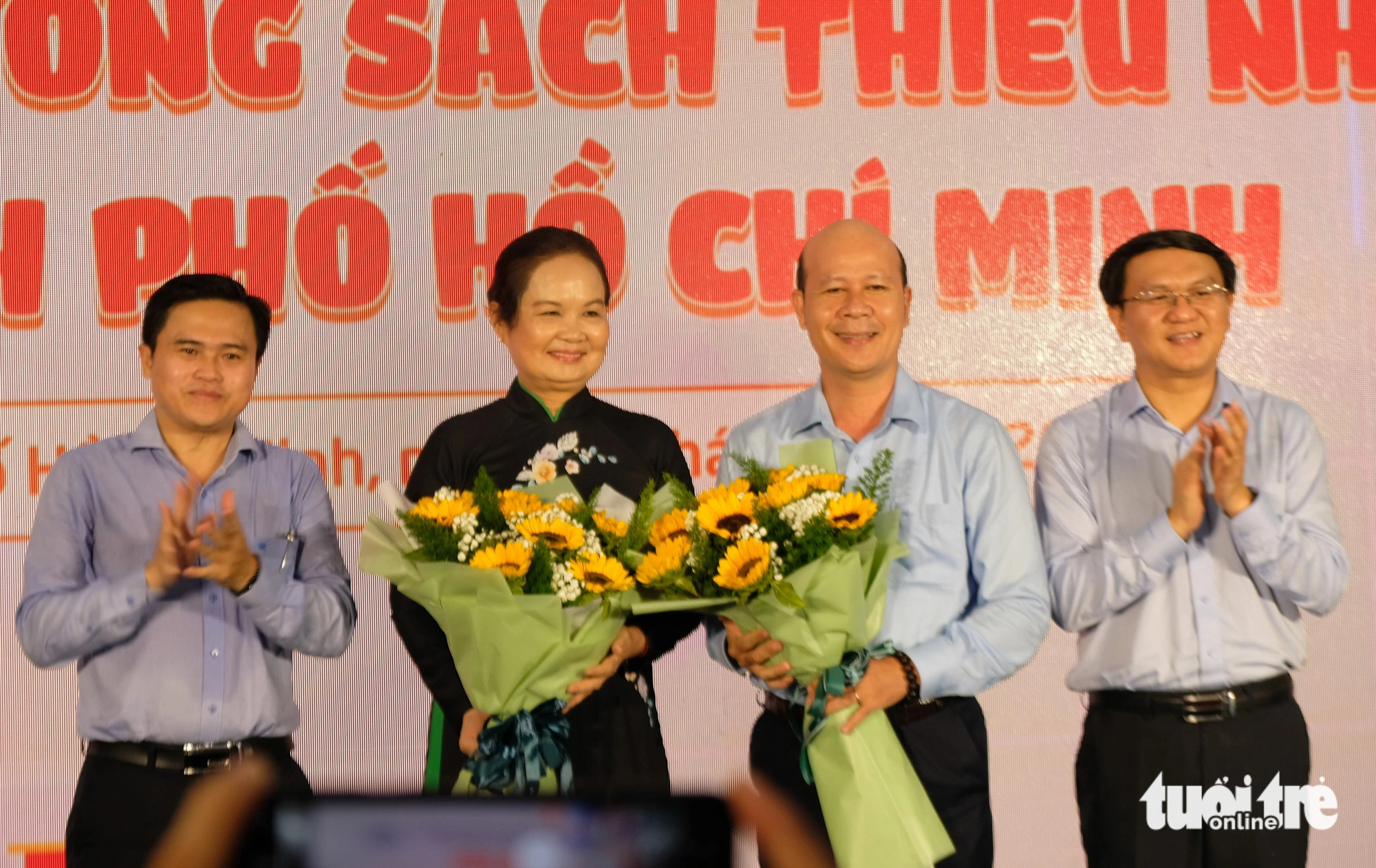 Trưởng Ban Văn hóa xã hội HĐND TP.HCM Cao Thanh Bình (bìa trái) và Giám đốc Sở Thông tin và Truyền thông TP.HCM Lâm Đình Thắng (bìa phải) tặng hoa cho đại diện hội đồng chuyên môn Giải thưởng sách thiếu nhi TP.HCM là bà Trịnh Bích Ngân và PGS.TS Bùi Thanh Truyền - Ảnh: LINH ĐOAN