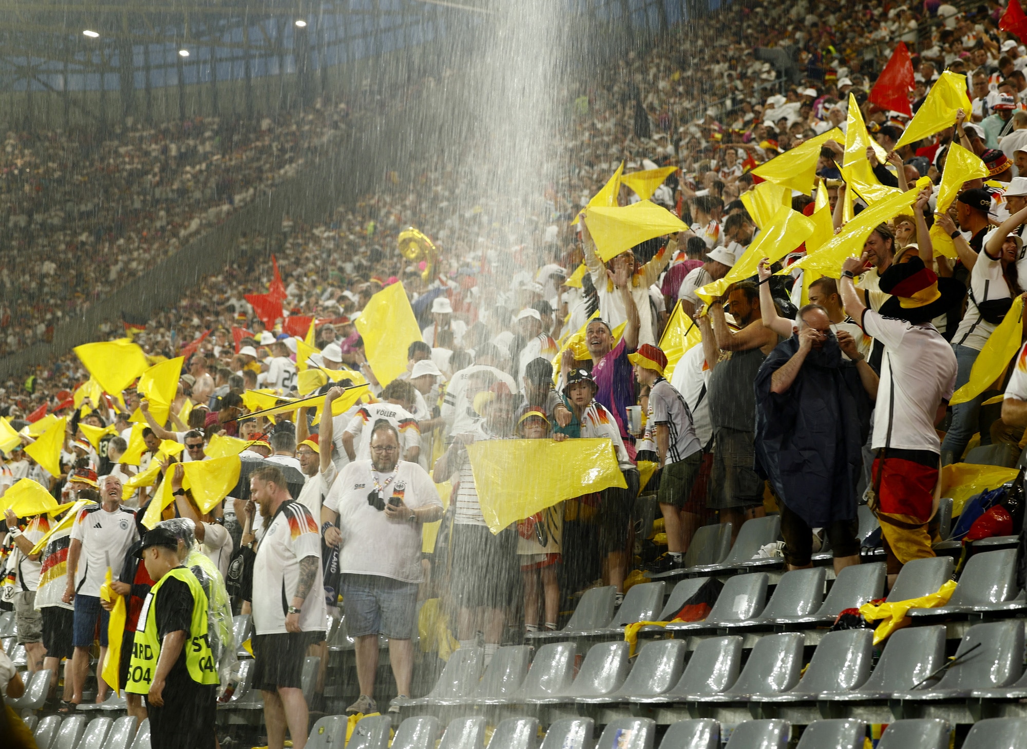 Mưa trút xuống khán đài sân Signal Iduna Park khiến các cổ động viên phải tìm chỗ trú - Ảnh: REUTERS