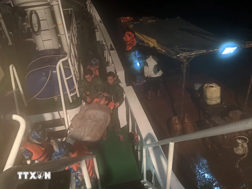 Traslado del paciente Nguyen Van Nhan del barco pesquero al barco 468 (izquierda) para llevarlo a la isla de Truong Sa para recibir tratamiento. (Foto: VNA)