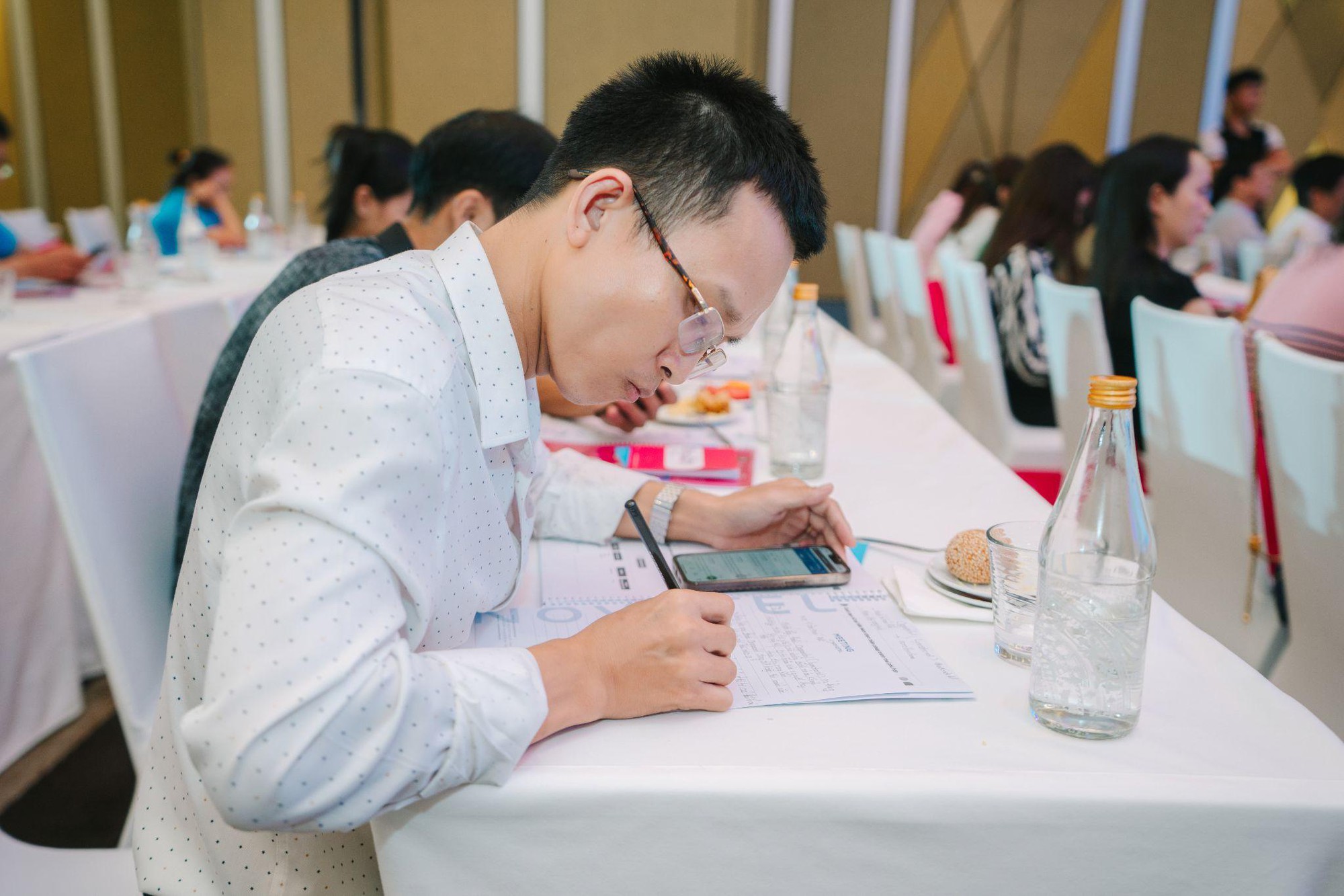 A person sitting at a table writing on his phone  Description automatically generated