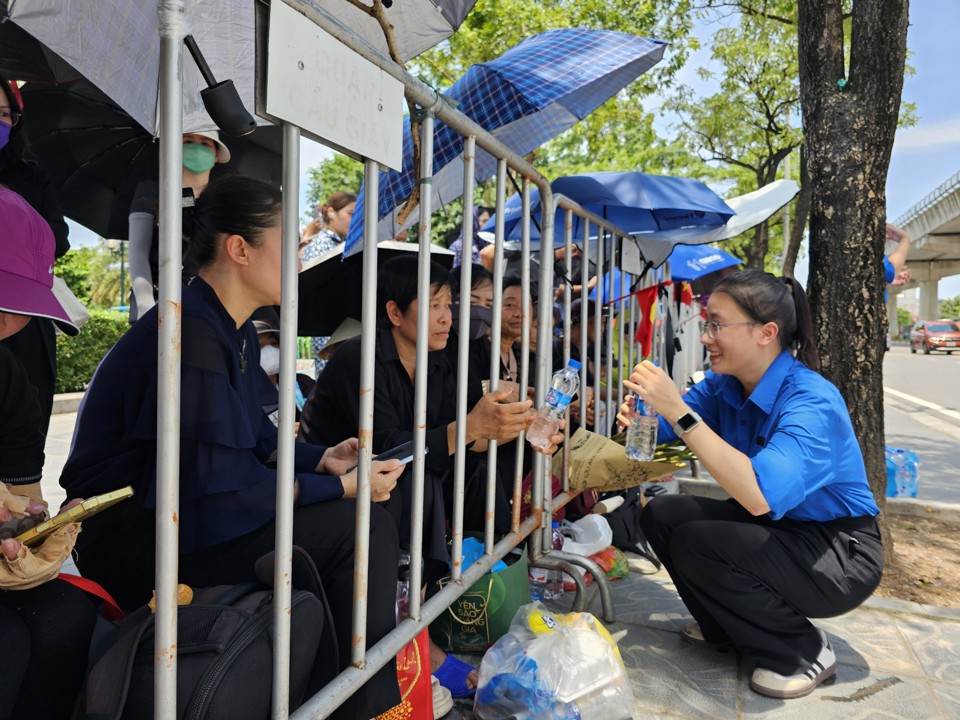 Thanh niên tình nguyện tiếp nước cho người dân chờ tiễn biệt Tổng Bí thư Nguyễn Phú Trọng trên đường Lê Đức Thọ. Ảnh: Quân Thủy