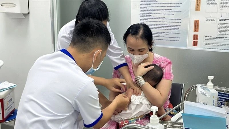 Nhân viên y tế đang tiêm vaccine phòng sởi cho trẻ