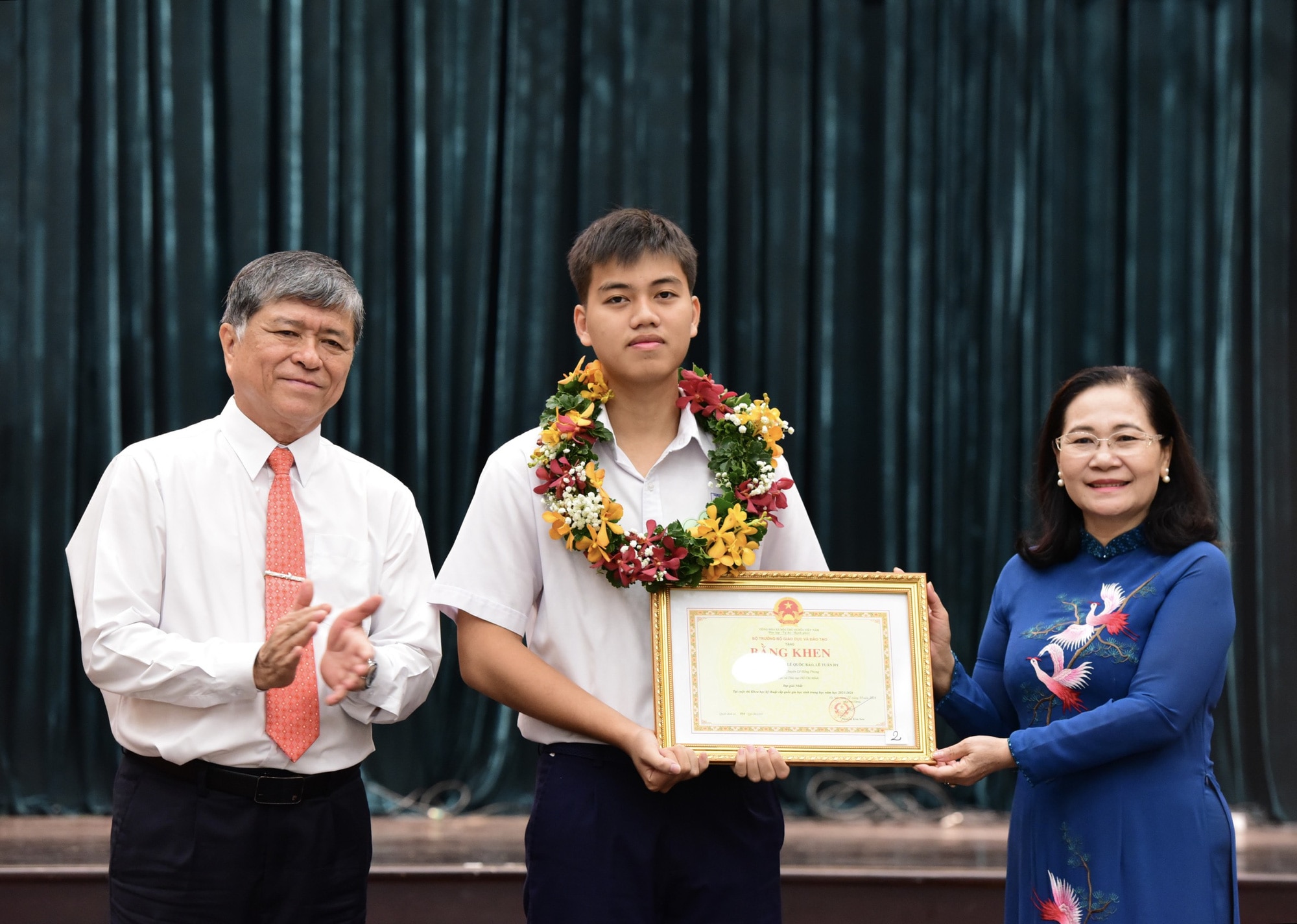 Bà Nguyễn Thị Lệ - phó bí thư Thành ủy TP.HCM, chủ tịch HĐND TP.HCM và ông Nguyễn Văn Hiếu - giám đốc Sở Giáo dục và Đào tạo, trao bằng khen cho em Lê Tuấn Hy - học sinh Trường THPT chuyên Lê Hồng Phong - Ảnh: DUYÊN PHAN