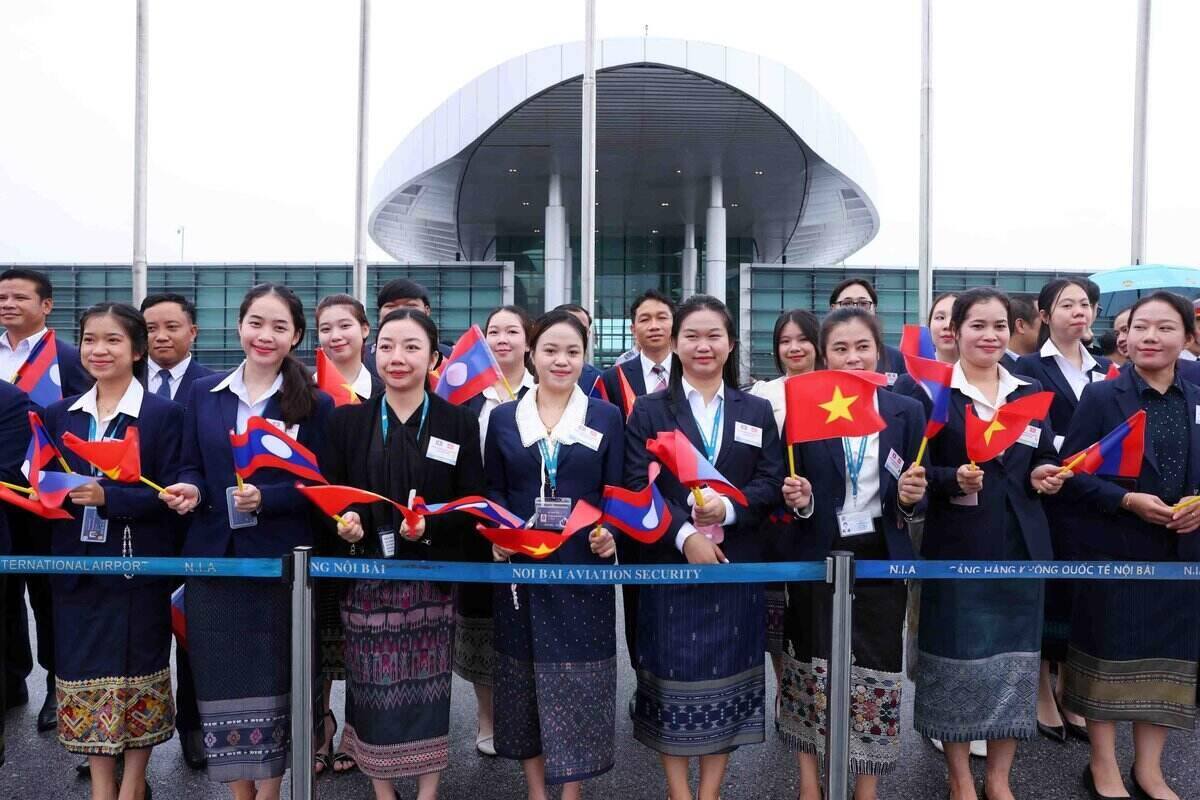 Cán bộ, nhân viên Đại sứ quán và đông đảo lưu học sinh Lào ra sân bay quốc tế Nội Bài đón Tổng Bí thư, Chủ tịch nước Lào Thongloun Sisoulith cùng Phu nhân cùng đoàn đại biểu cấp cao Đảng, Nhà nước Lào thăm cấp Nhà nước tới Việt Nam. Ảnh: TTXVN