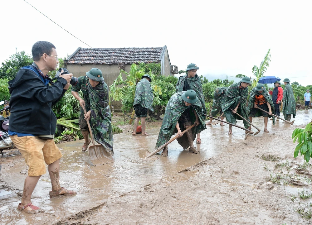 Phóng viên Danh Lam, Cơ quan thường trú Bắc Giang, tác nghiệp tại hiện trường khắc phục hậu quả mưa lũ tại thôn Khả Lã, xã Tân Lập, Lục Ngạn, Bắc Giang. (Ảnh: TTXVN)