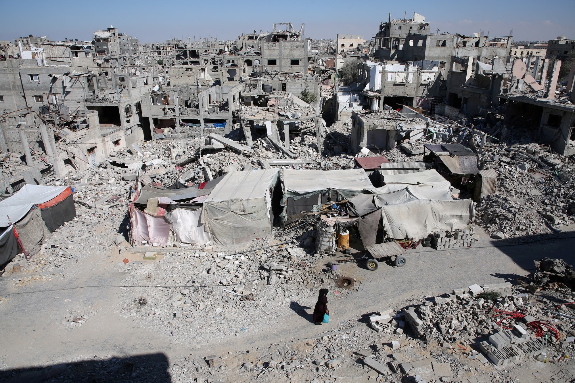 Palestinians walk past the rubble of houses destroyed by Israeli strikes, in Khan Younis