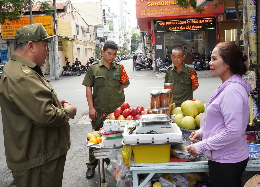 Lực lượng bảo vệ an ninh trật tự ở cơ sở phường Nguyễn Thái Bình, quận 1 trao đổi với người dân. Ảnh: THU HƯỜNG