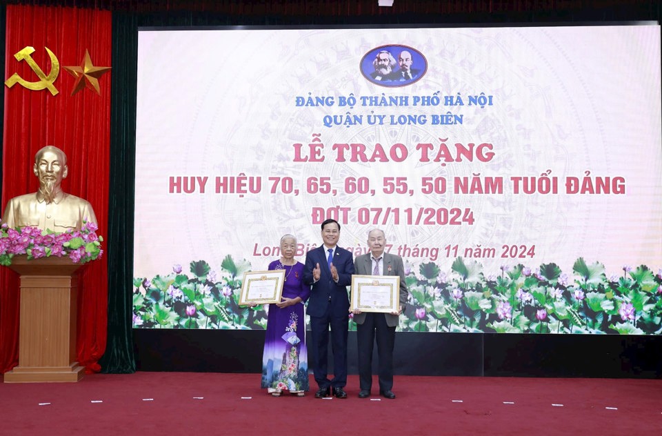 Phó Bí thư Thường trực Quận ủy Long Biên Ngô Mạnh Điềm trao Huy hiệu 65 năm tuổi Đảng tặng hai đảng viên.