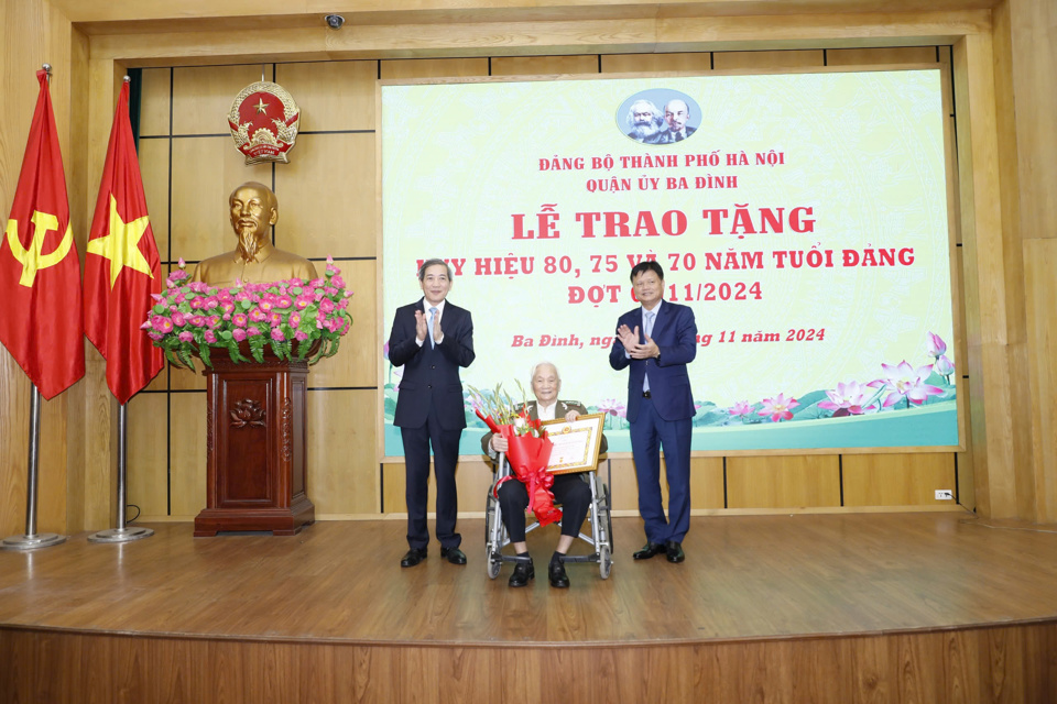 Trưởng ban Tổ chức Thành ủy Vũ Đức Bảo (bên phải) và Bí thư Quận ủy Ba Đình Hoàng Minh Dũng Tiến (bên trái) trao Huy hiệu 80 năm tuổi Đảng tặng đảng viên lão thành.