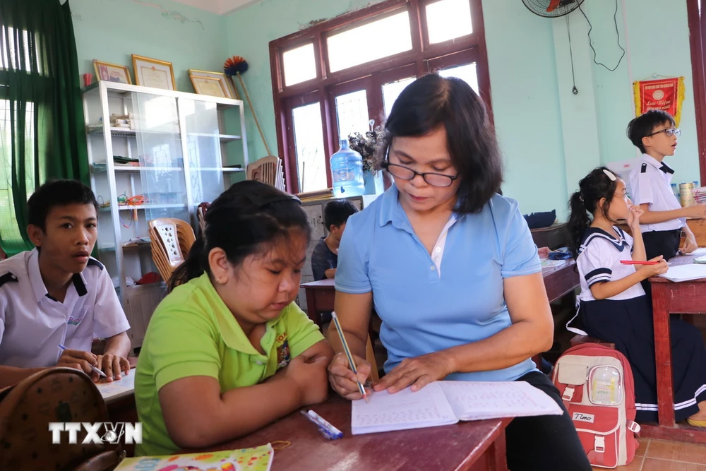 Cô giáo Nguyễn Thị Hương, xã Hành Minh, huyện Nghĩa Hành, hướng dẫn học sinh viết bài.( Ảnh: Đinh Hương/ TTXVN)