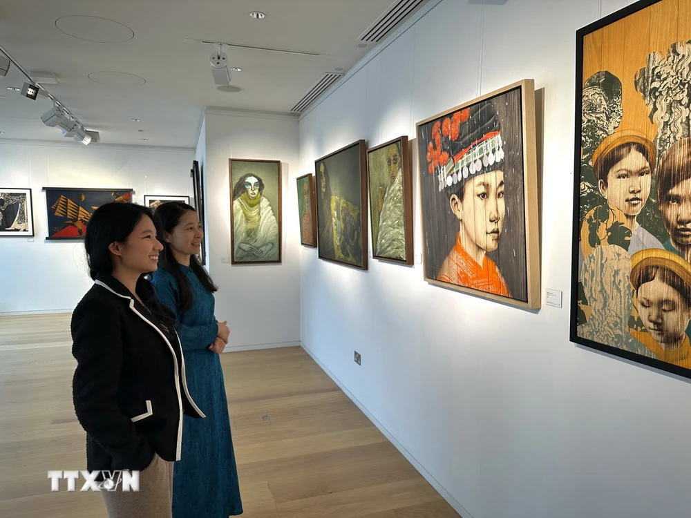 Nhân viên phòng tranh Thăng Long Art Gallery giới thiệu về các tác phẩm với khách tham quan. (Ảnh: TTXVN phát)