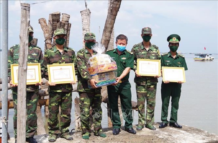 Đại tá Bùi Văn Vũ (thứ ba từ phải sang), Phó Chính ủy Bộ đội Biên phòng Tiền Giang trao tặng giấy khen và quà cho 4 cán bộ, chiến sĩ đang làm nhiệm vụ tại chốt chống dịch trên biển. (Ảnh tư liệu: TTXVN)