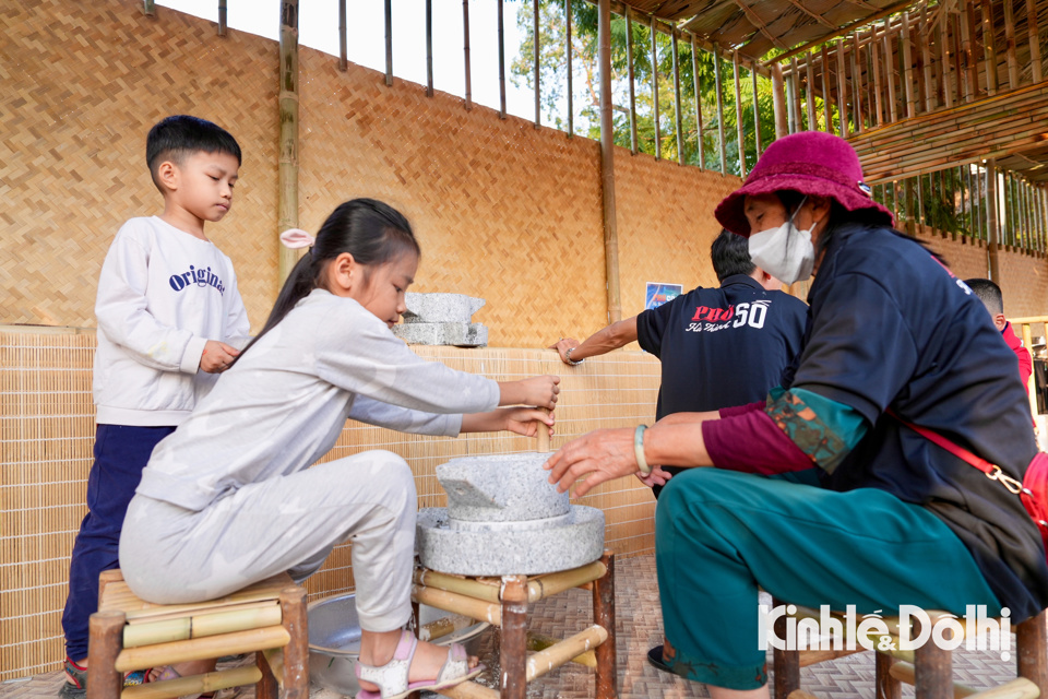 Nhiều gian hàng làng nghề có những trải nghiệm cho người dân và du khách. Một em nhỏ tham gia trải nghiệm xay bột bằng cối đá.