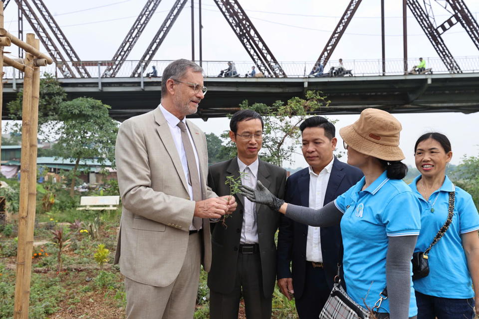 Đại sứ Pháp trao đổi với người dân khu vực về khu vui chơi dưới chân cầu Long Biên và các loại thực vật, thảo dược trồng lân cận. Ảnh: Khánh Huy