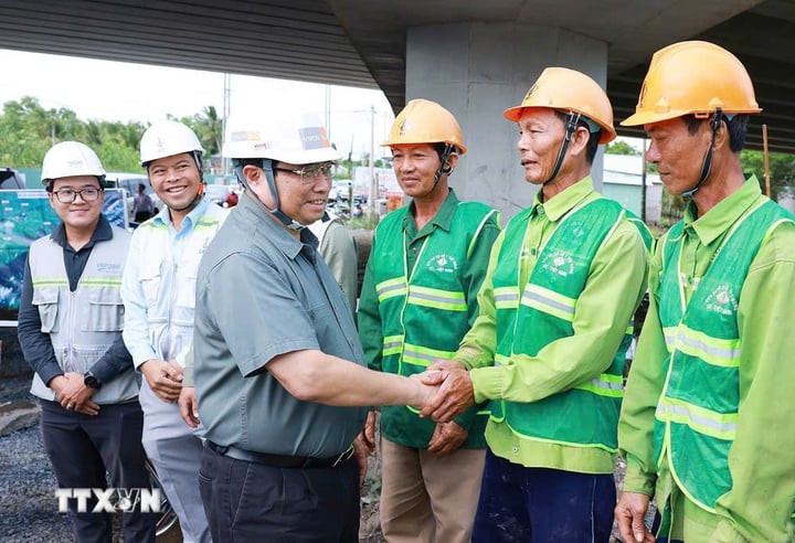 Thủ tướng Phạm Minh Chính với công nhân thi công cao tốc Cần Thơ-Hậu Giang. (Ảnh: Dương Giang/TTXVN)