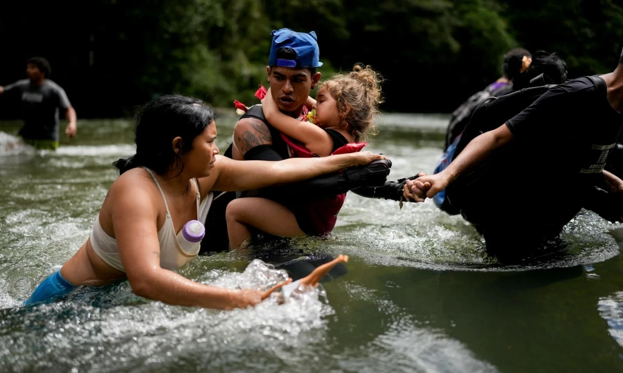 Alvaro Calderini từ Venezuela bế cháu gái qua sông sau khi họ đi bộ qua Darien Gap, tìm đường di cư đến Mỹ. (Nguồn: AP)