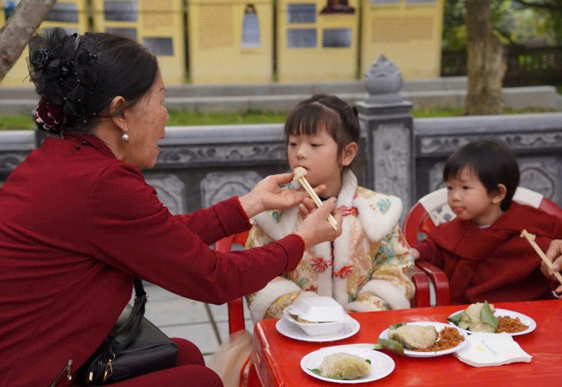 Các em nhỏ rất thích thú khi ăn bánh chưng tại lễ hội