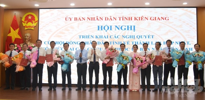 Bí thư Tỉnh ủy Kiên Giang Nguyễn Tiến Hải (thứ 6 từ trái qua) và Chủ tịch UBND tỉnh Kiên Giang Nguyễn Thanh Nhàn (thứ 7 từ trái qua) trao quyết định và tặng hoa chúc mứng các lãnh đạo sở mới được thành lập, hợp nhất. Ảnh: Trung Chánh. 