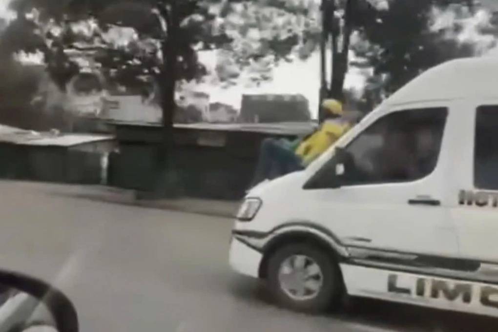 Người đàn ông ngồi trên nắp capo ô tô đang chạy trên Đại lộ Thăng Long - 1 Người đàn ông ngồi trên nắp capo ô tô đang chạy trên Đại lộ Thăng Long - 1